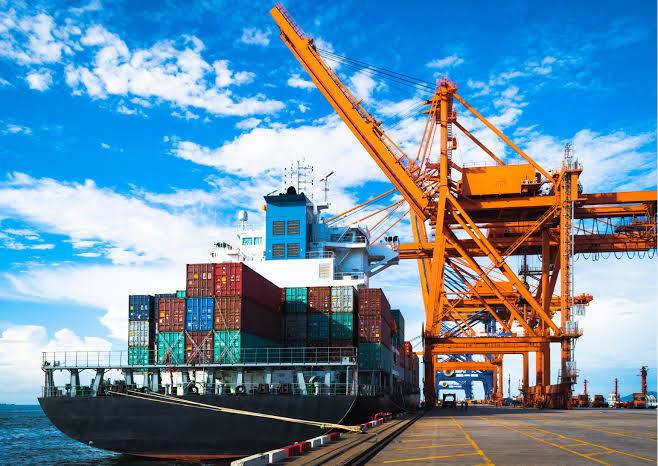 Cargo chargé de conteneurs à quai, sous une grue portuaire